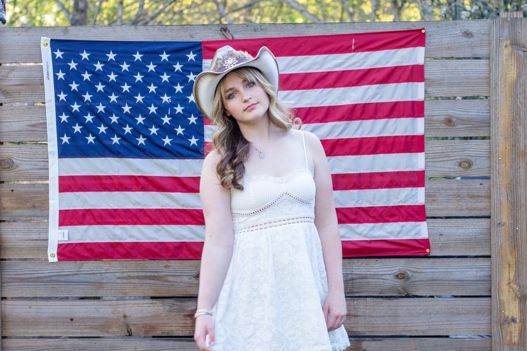 Stella Gavitt in a cowboy hat in front of an American flag