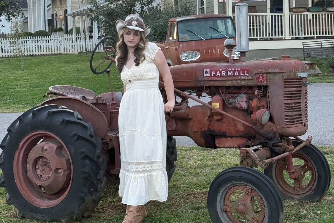 Stella Gavitt beside a vintage Farmall tractor at golden hour in Leiper's Fork, Tennessee